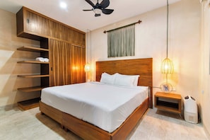 A bedroom with a wooden bed frame, a ceiling fan, a bedside table with a lamp, and a built-in wardrobe with shelves. - Bright Tulum 2BR - Rooftop Pool near Aldea Zama (Tulum)
