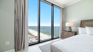 A hotel room with a large window offering a view of the beach and pier.