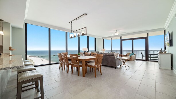 A spacious living area with a large dining table, comfortable seating, and a view of the ocean.