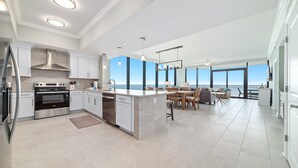 A modern kitchen with stainless steel appliances, a large island, and a dining area with a view.