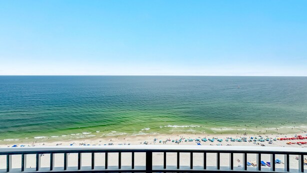 A beach with a clear view of the ocean, a sandy shore, and a railing in the foreground. - New Complex!  Beachfront 4BR, Lazy River and Water Slide! (Gulf Shores)