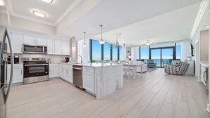 A modern kitchen with stainless steel appliances, a central island, and a dining area with a view.