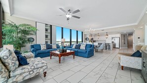 A spacious living room with a large sofa, a coffee table, and a ceiling fan. - New Complex!  Beachfront 4BR, 5TH FLOOR!, Lazy River and Water Slide! (Gulf Shores)