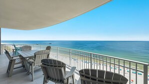 Un balcon avec un espace salon extérieur et une vue sur la plage et l’océan.