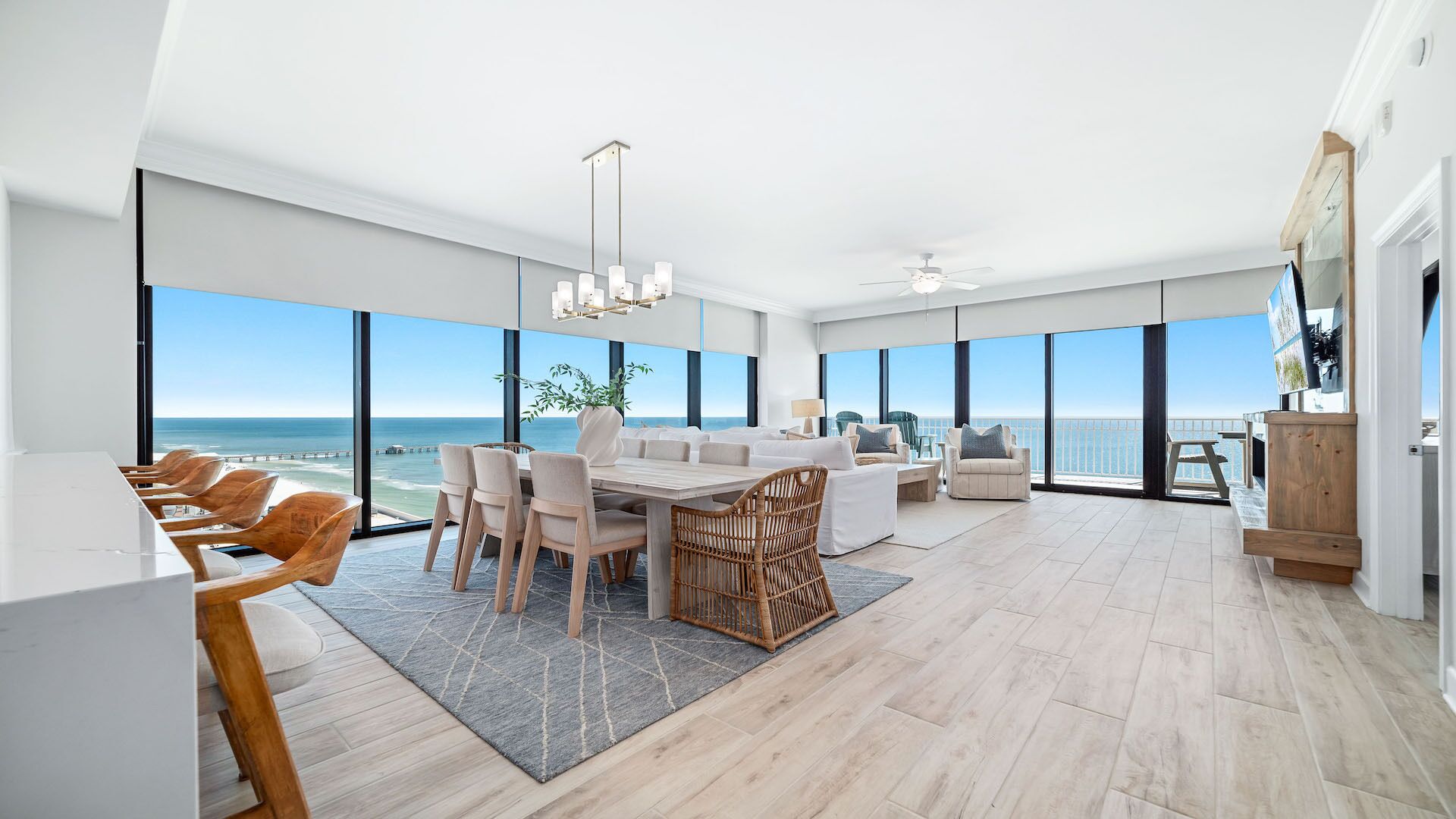 A spacious living area with a large dining table, comfortable seating, and a view of the ocean.