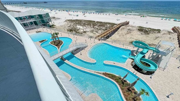 Een resort met meerdere zwembaden, een glijbaan en uitzicht op het strand.