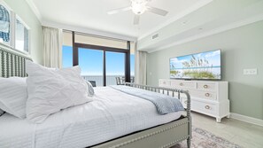 Une chambre à coucher avec un lit, une commode, un téléviseur et une vue sur l’océan.