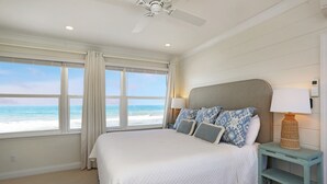 Un dormitorio con una cama grande, una mesita de noche con lámpara y vistas al océano.
