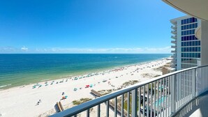 A beach view from a balcony with a pool and a building with multiple balconies. - New Complex!  Beachfront 3BR Beauty! LAZY RIVER and WATER SLIDE!! (Gulf Shores)