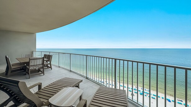 A balcony with a view of the ocean, a table, chairs, and a bench. - New Complex!  Beachfront 3BR Beauty! LAZY RIVER and WATER SLIDE!! (Gulf Shores)