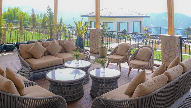 A covered outdoor seating area with wicker furniture and hanging light fixtures. - RajBagh Shimla (Shimla)