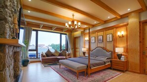 A bedroom with a four-poster bed, a sofa, a stone wall, and a large window with a view. - RajBagh Shimla (Shimla)