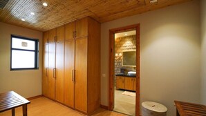 A room with wooden cabinets, a small table, and a wicker stool. - RajBagh Shimla (Shimla)