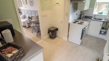 Cocina compacta con estufa, pileta y comedor con mesa y sillas.