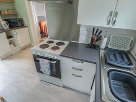 Una cocina con estufa, horno, pileta y una encimera con un bloque de cuchillos y dispensador de toallas de papel.