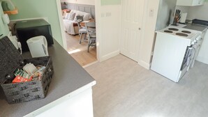 A compact kitchen with a stove, a dining area with a table and chairs, and a living room with a sofa and a coffee table.