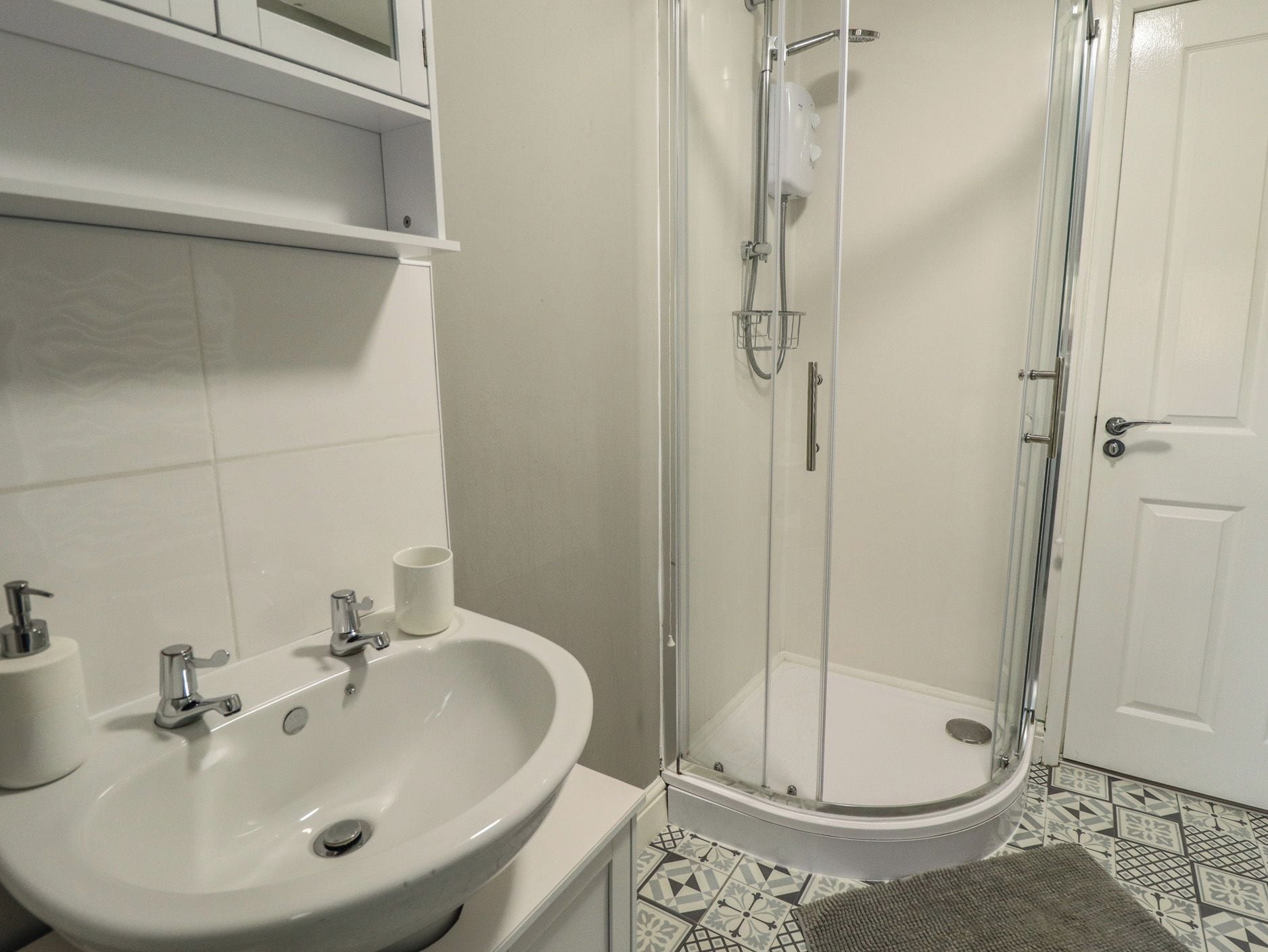 Un baño con lavamanos, inodoro y ducha con mampara de vidrio.