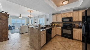 A spacious kitchen with a central island, modern appliances, and a view to the outside. - Crystal Shores West 208 (Gulf Shores)