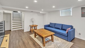 Un soggiorno moderno con un divano blu, un tavolino in legno e una scala che conduce a un altro piano.