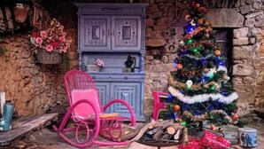 A rustic room with a stone wall, a blue cabinet, a pink rocking chair, a Christmas tree, and a fireplace. - Mas la Mayanne in the heart of the vineyards. (Vénéjan)