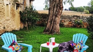 A garden with two blue chairs, a white table, and a black lantern. - Mas la Mayanne in the heart of the vineyards. (Vénéjan)