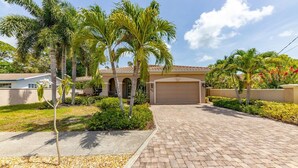 A residential property with a paved driveway, palm trees, and a garage. - Sapphire Shores 3 Bedroom Home (Sarasota)