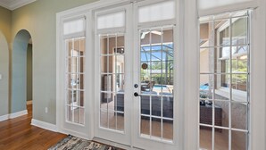 A room with a large sliding glass door leading to a patio with a pool and outdoor furniture. - Sapphire Shores 3 Bedroom Home (Sarasota)