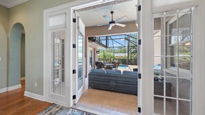 A spacious entryway with a view of an outdoor patio area, including a pool and outdoor furniture. - Sapphire Shores 3 Bedroom Home (Sarasota)