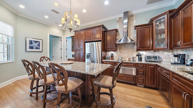 A modern kitchen with wooden cabinets, a stainless steel refrigerator, a built-in oven, and a granite countertop. - Sapphire Shores 3 Bedroom Home (Sarasota)