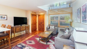 Una sala de estar con una mesa de comedor de madera, un televisor de pantalla plana, un sofá y una mesa de centro.