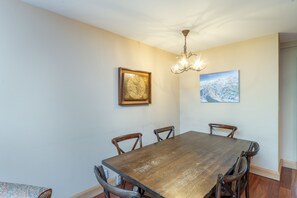 A dining area with a wooden table and chairs, a chandelier, and two framed pictures on the wall. - Cimarron Lodge 35 2 Bedroom Condo (Telluride)