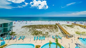 A beach resort with a pool area, beach chairs, and a wooden pier. - Phoenix Gulf Shores Ii 404 3 Bedroom Condo (Gulf Shores)