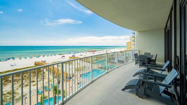 A balcony with a view of the beach, lounge chairs, and a pool area. - Phoenix Gulf Shores Ii 404 3 Bedroom Condo (Gulf Shores)