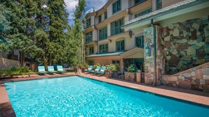 Une piscine avec des chaises longues et un mur en pierre.