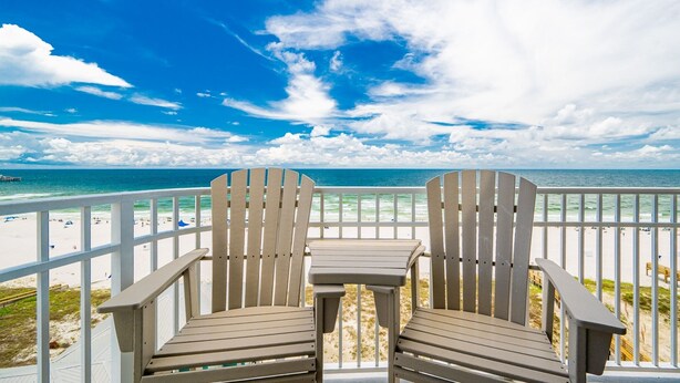 Two Adirondack chairs facing a beach with a white railing and a view of the ocean. - Phoenix Gulf Shores Ii 705 4 Bedroom Condo (Gulf Shores)