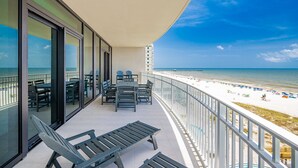 Un balcon avec vue sur la plage, une table avec des chaises et un fauteuil de relaxation.