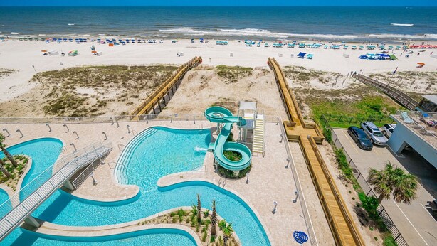 Un complexe hôtelier de bord de mer doté d’une grande piscine, d’un toboggan aquatique et offrant une vue sur l’océan.