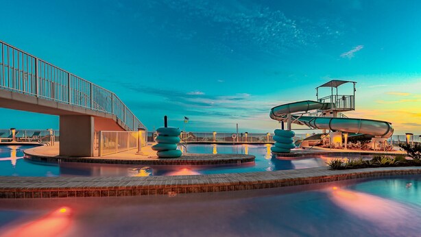 Un parque acuático con un puente, toboganes y una piscina.