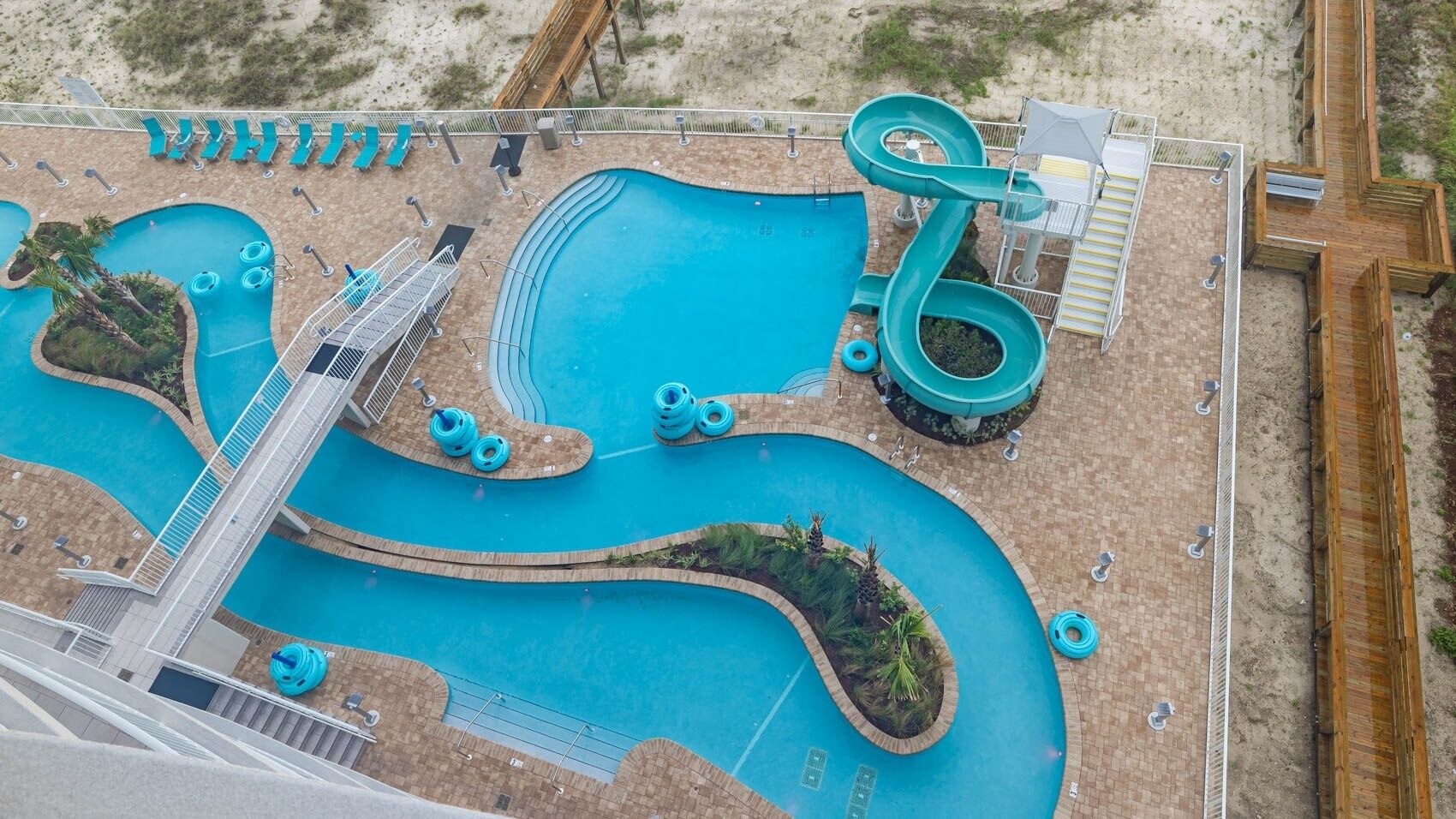 An aerial view of a water park with multiple pools, slides, and a wooden deck area.