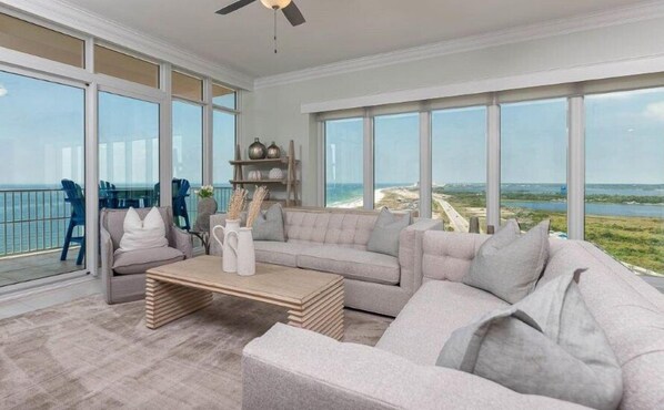Enjoy ocean views from the spacious living area with a large window, featuring a sofa, armchair, and coffee table.