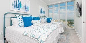Relax in a serene bedroom with a large bed, framed artworks, and a stunning landscape view.