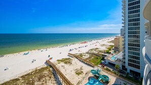 Un resort en la playa con piscina, sombrillas y un paseo marítimo.