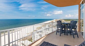 Enjoy stunning beach views from this balcony with a table and chairs.