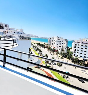 Un paysage urbain côtier avec des bâtiments modernes, une plage et un ciel bleu dégagé.