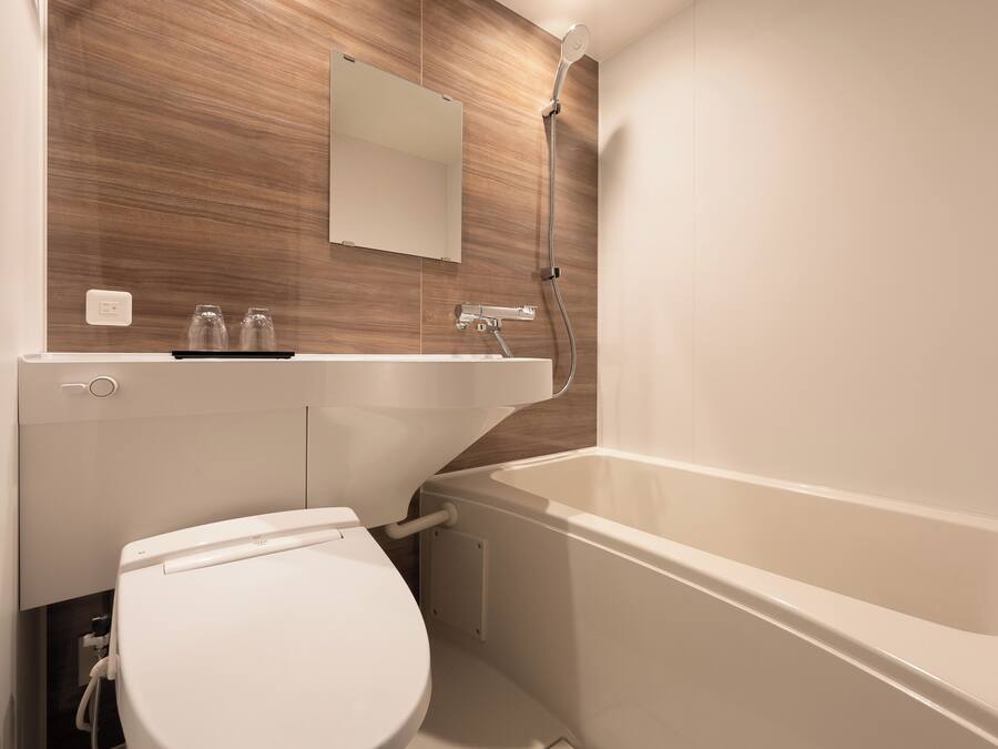 Une salle de bain moderne avec des toilettes blanches, une baignoire et un mur en bois.