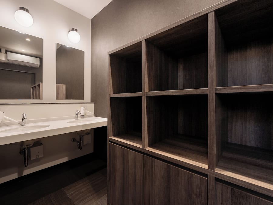 A modern bathroom with two sinks, a mirror, and built-in wooden shelves.