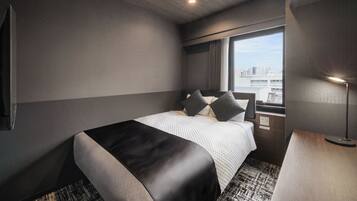 Una habitación de hotel moderna con una cama grande, un escritorio y una ventana con vista a la ciudad.