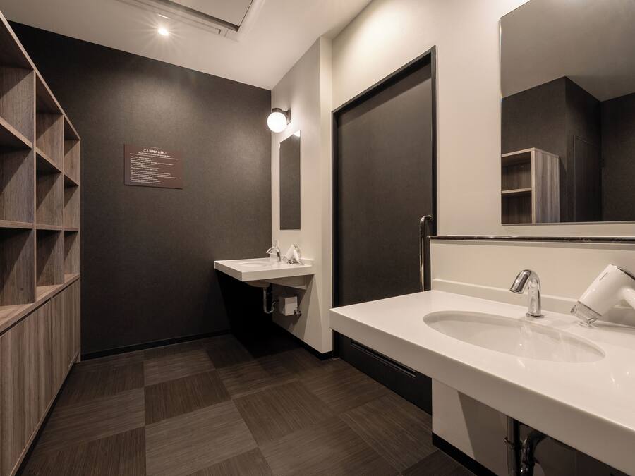 A modern bathroom with a large mirror, two sinks, and a built-in shelf unit.