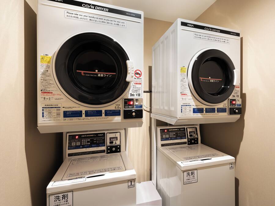 Two stacked coin dryers with instructions and a coin-operated washer.