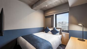 A hotel room with a bed, a desk, a window with a city view, and a ceiling with a wooden panel.